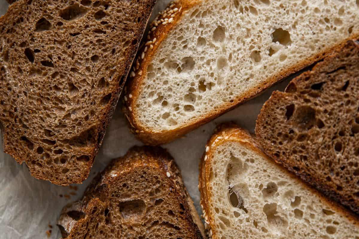 Slices of light and dark artisan bread arranged on crinkled parchment paper.
