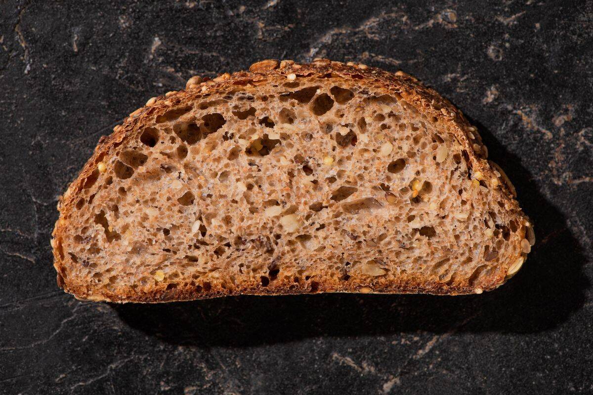 Close-up of a sliced whole grain bread loaf showing a dense, seeded crumb.