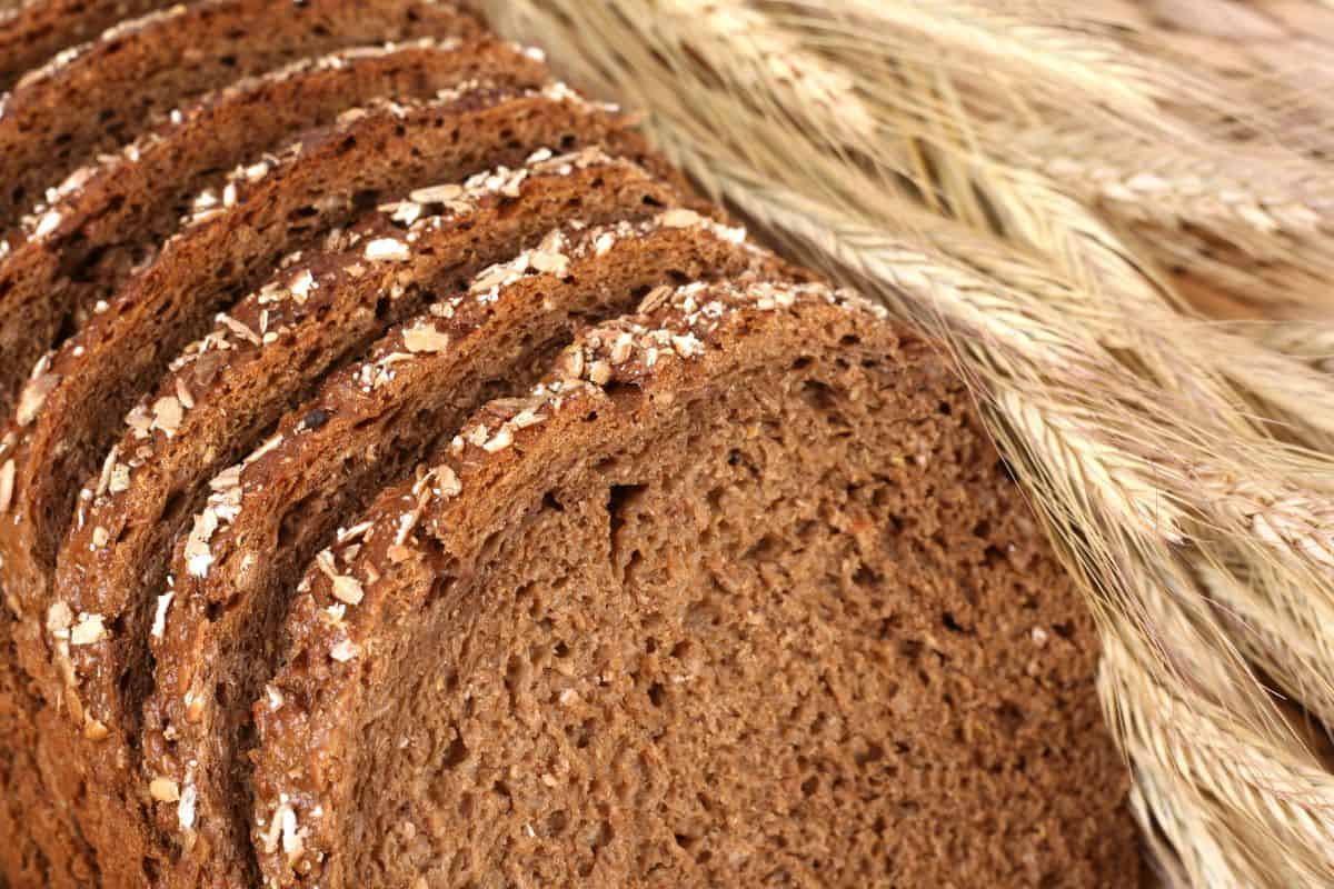 Close-up of sliced whole grain bread with visible seeds and wheat stalks.