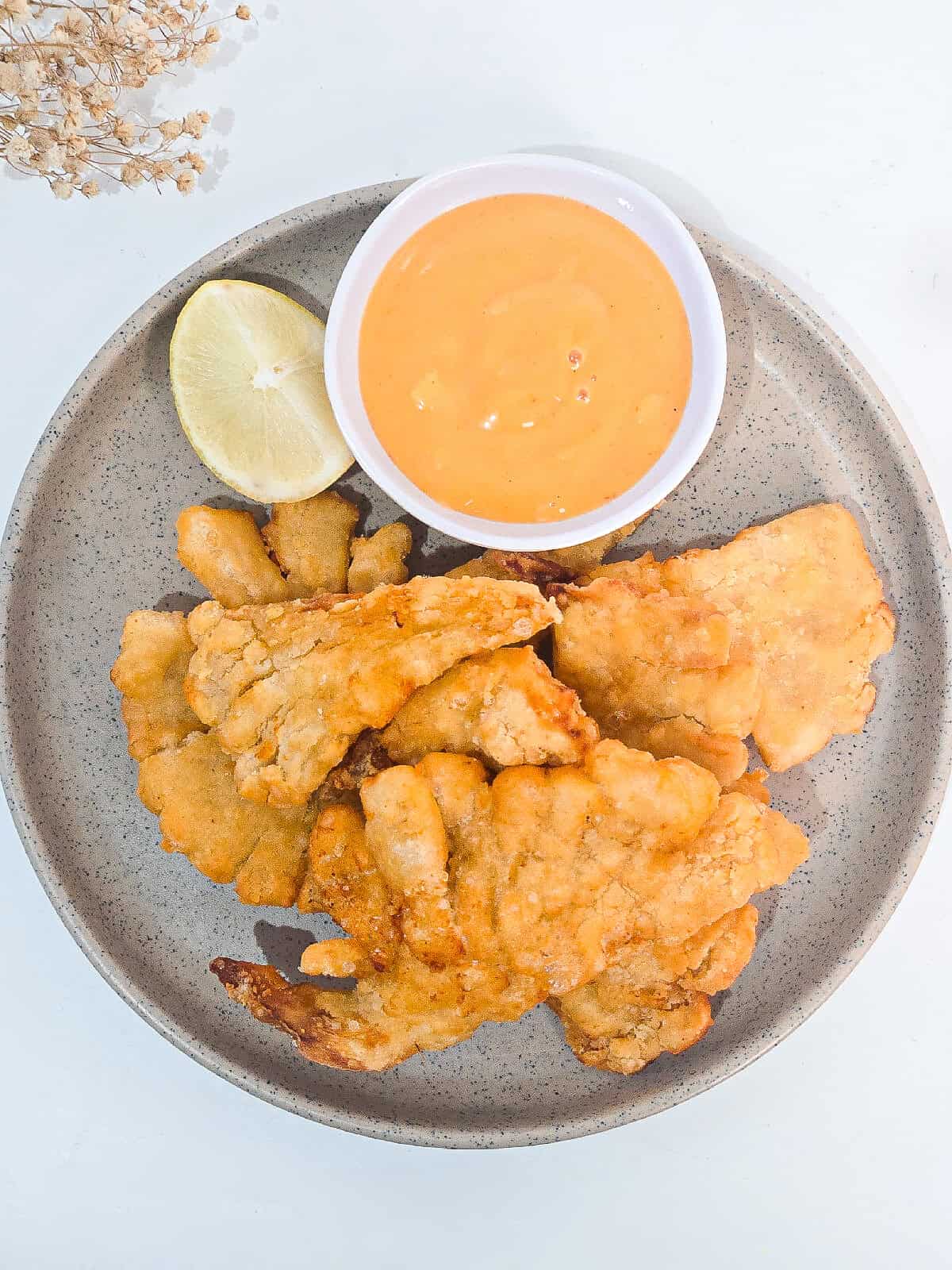 Crispy air fryer oyster mushrooms served with lemon wedges and creamy dipping sauce on a gray plate.