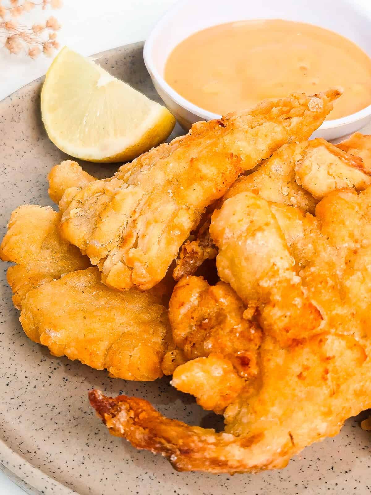 Golden air fryer oyster mushrooms plated with a creamy dipping sauce and fresh lemon.