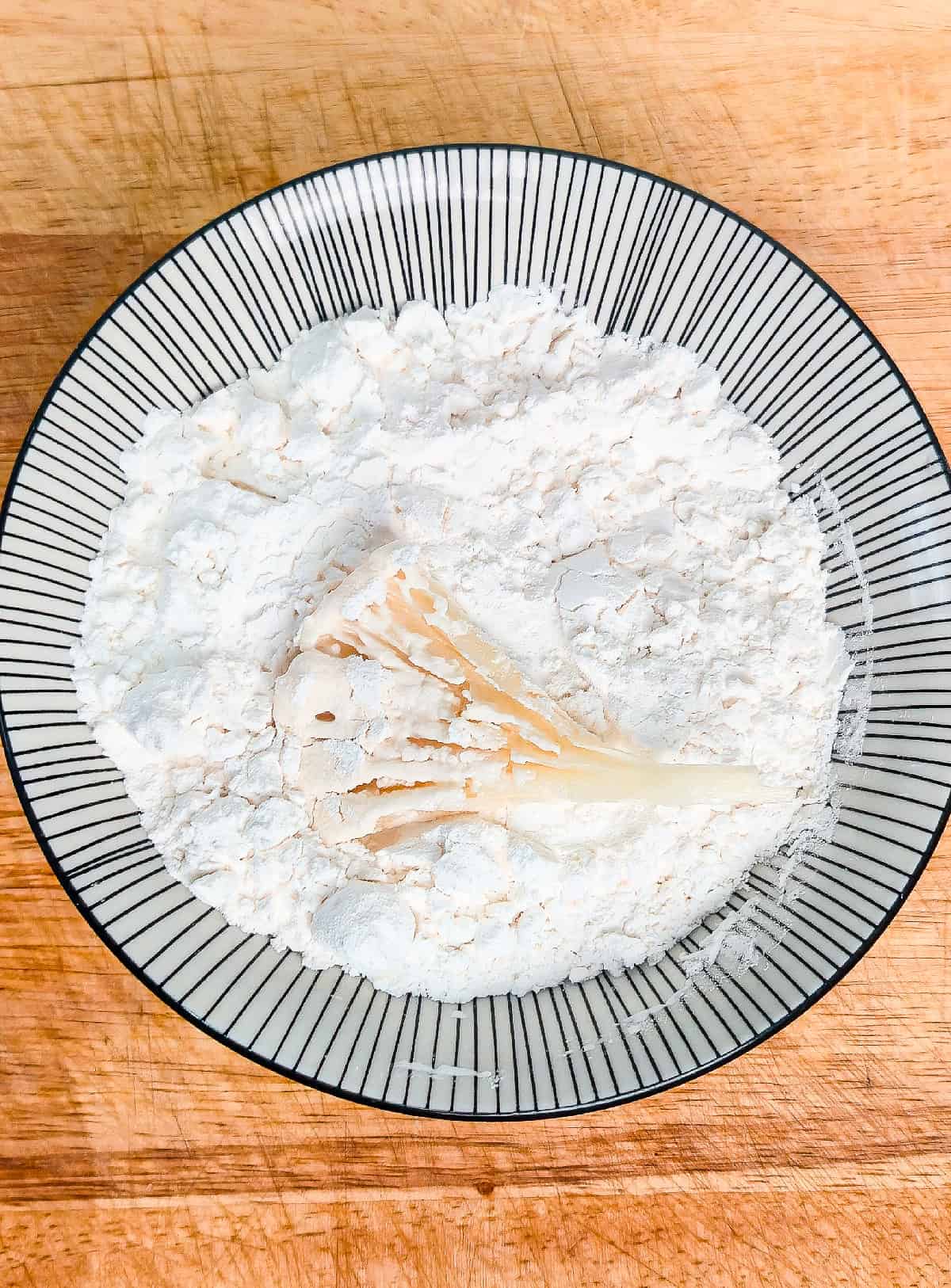 Oyster mushrooms being dredged in cornstarch mixture to coat evenly.