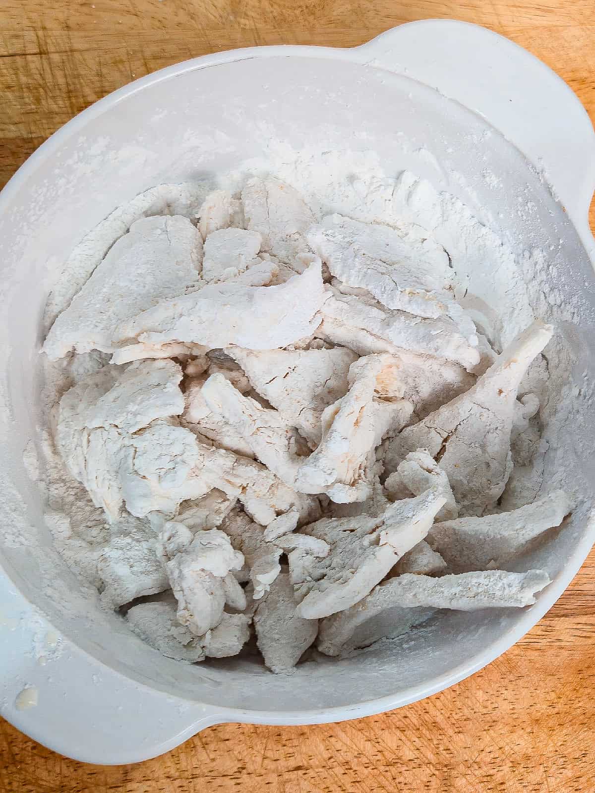 Cornstarch-coated oyster mushrooms resting in a bowl before air frying.