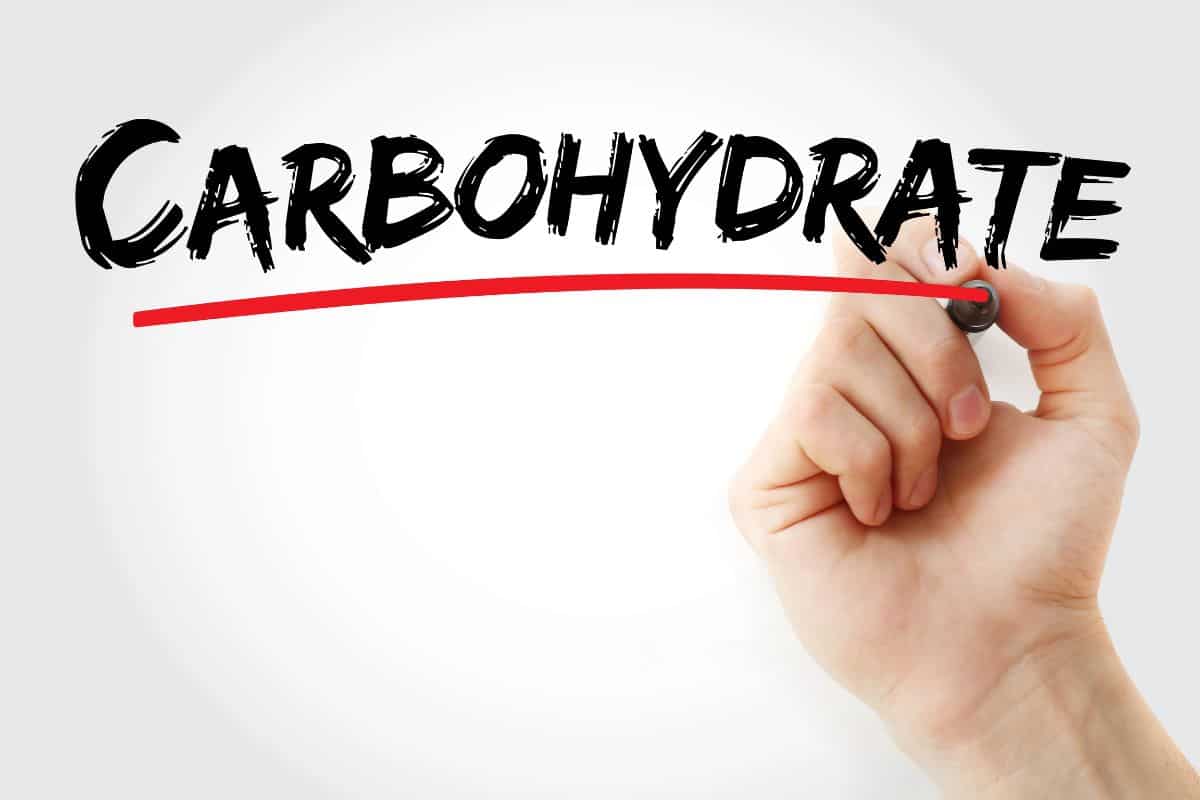A hand writes the word “CARBOHYDRATE” in bold black letters and underlines it in red on a white background.