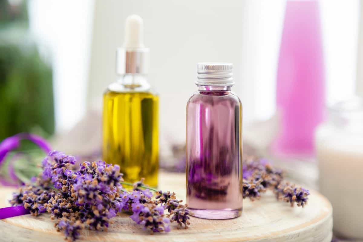 Two essential oil bottles displayed with fresh lavender on a wooden surface in a bright setting.