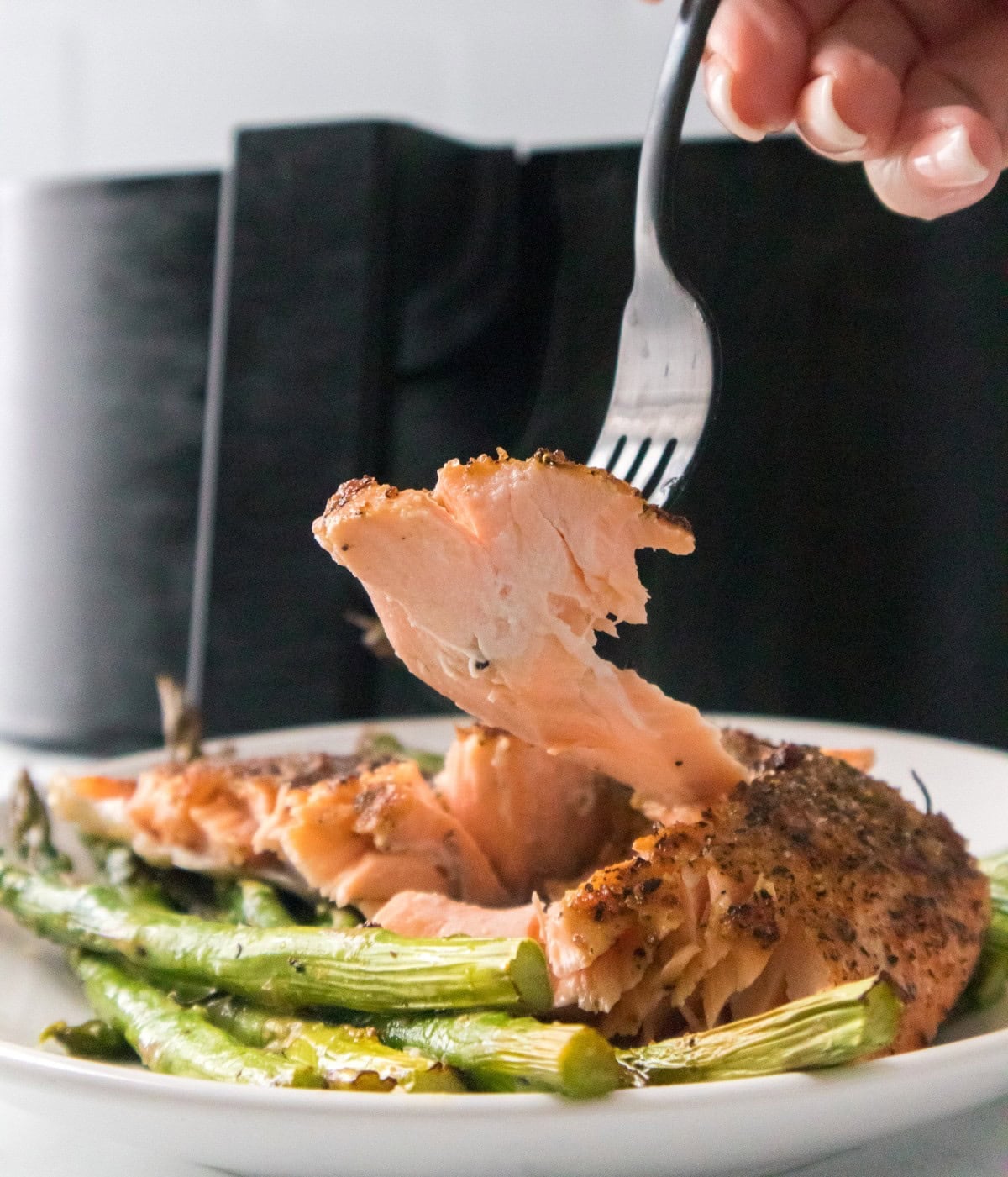 Close up of tender air fryer salmon with crispy seasoning and asparagus.
