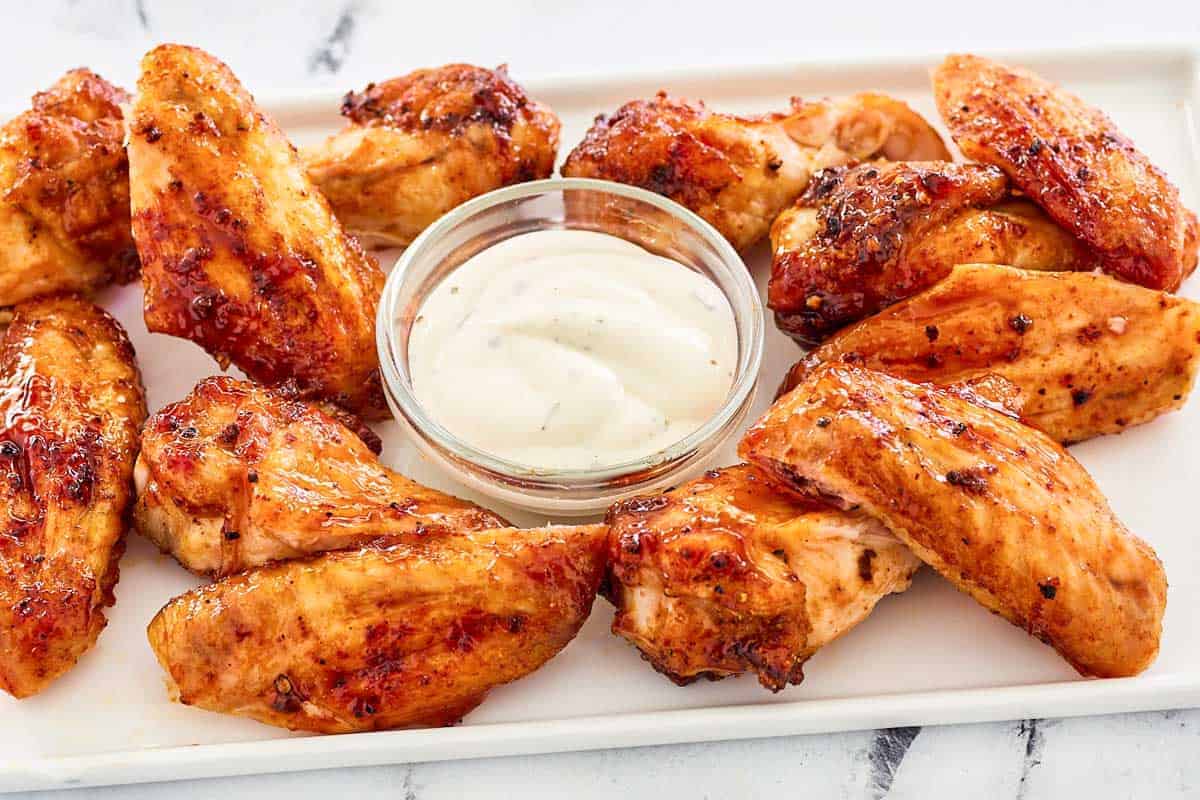 Oven-baked barbecue chicken wings glazed with sauce and served hot on a tray.