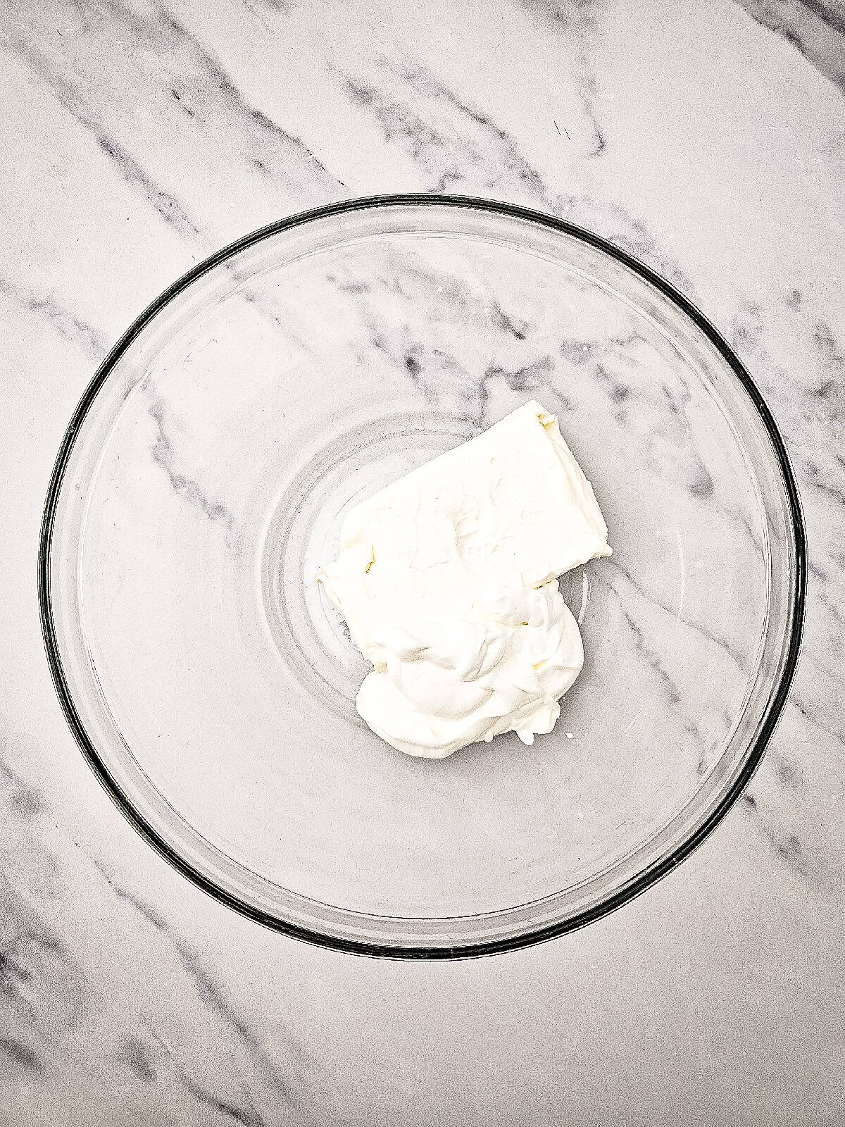 Cream cheese and sour cream placed in a glass mixing bowl.