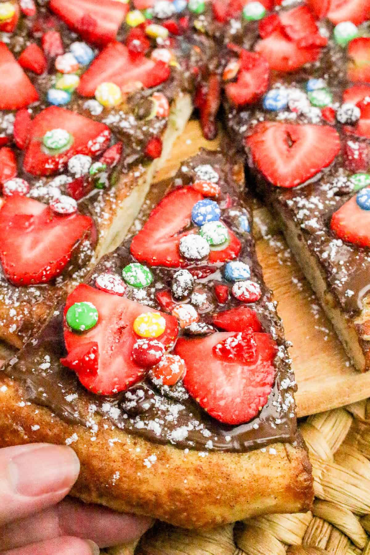 Easy homemade Nutella dessert pizza slices topped with strawberries, chocolate spread, and colorful candy.