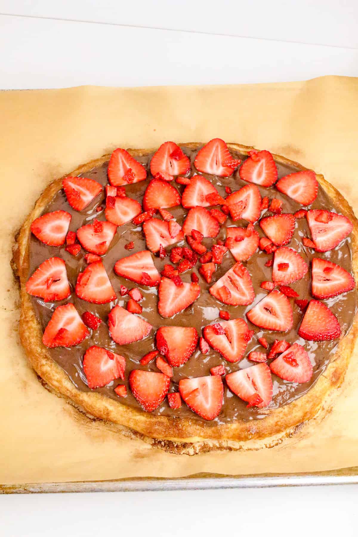 Homemade Nutella pizza topped with fresh sliced strawberries on a baked dessert pizza crust.