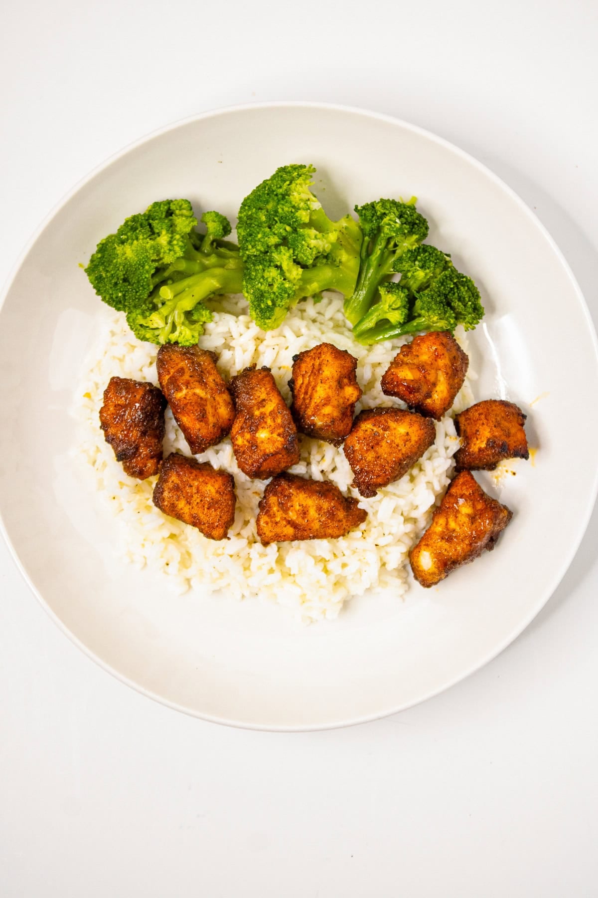 Air fryer salmon bites served over white rice with steamed broccoli on a white background.