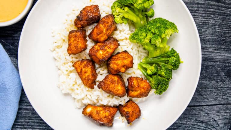 Air fryer salmon bites served over white rice with steamed broccoli in a white bowl.