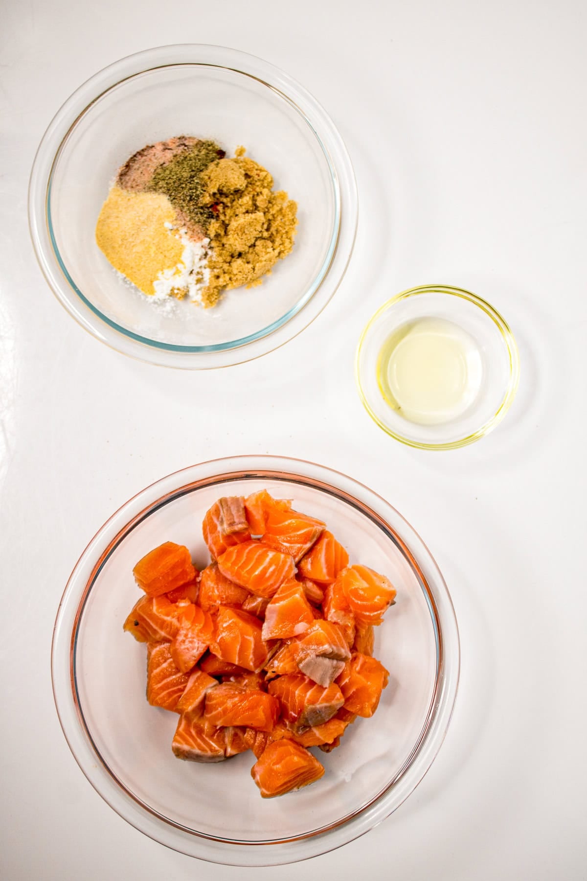 Dry seasoning mixture for air fryer salmon bites with brown sugar, garlic powder, paprika, cornstarch, salt, and pepper in a glass bowl.