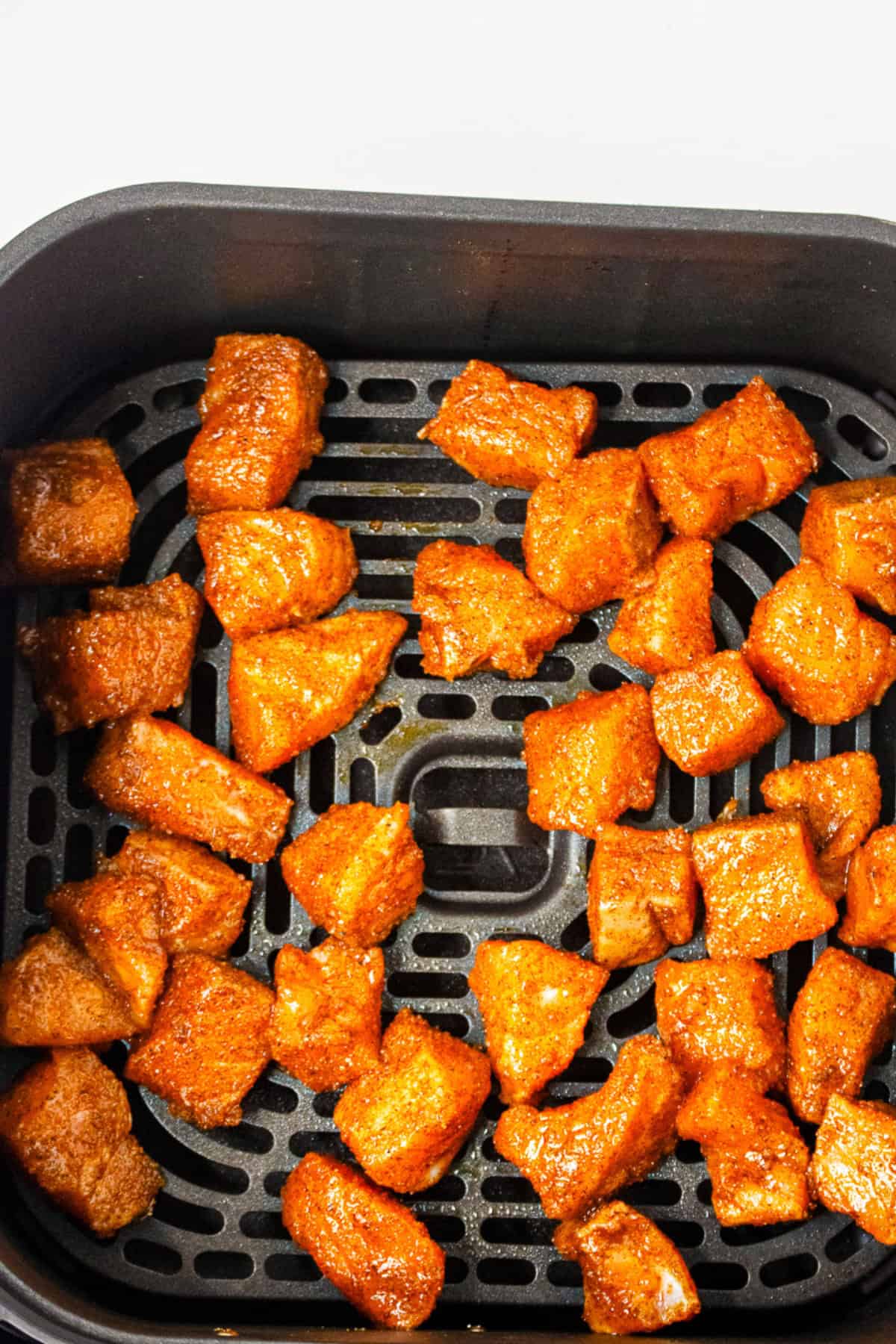Crispy air fryer salmon bites cooked in an air fryer basket.