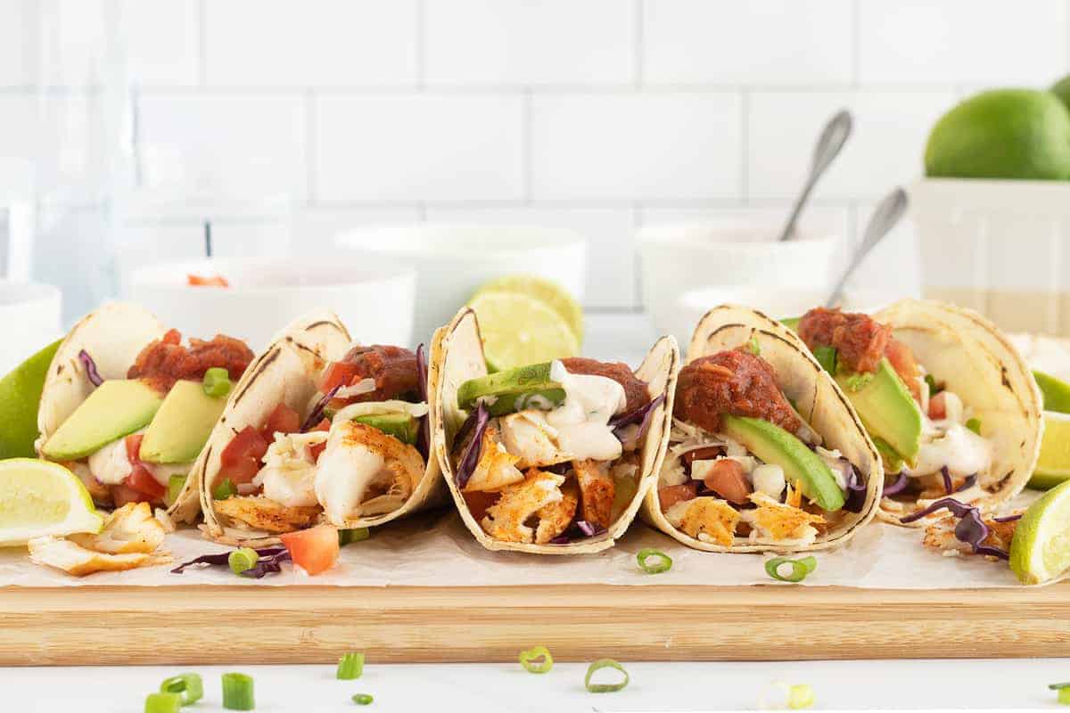 Soft tacos filled with seasoned fish and toppings.