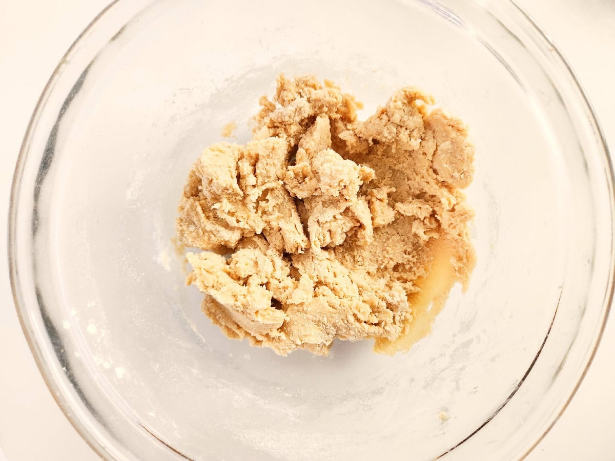 Cookie dough forming in a glass bowl after mixing wet and dry ingredients.