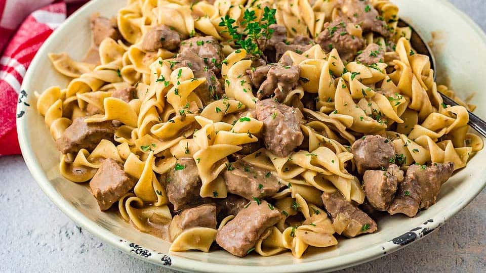 Beef and noodles cooked with mushrooms in slow cooker.