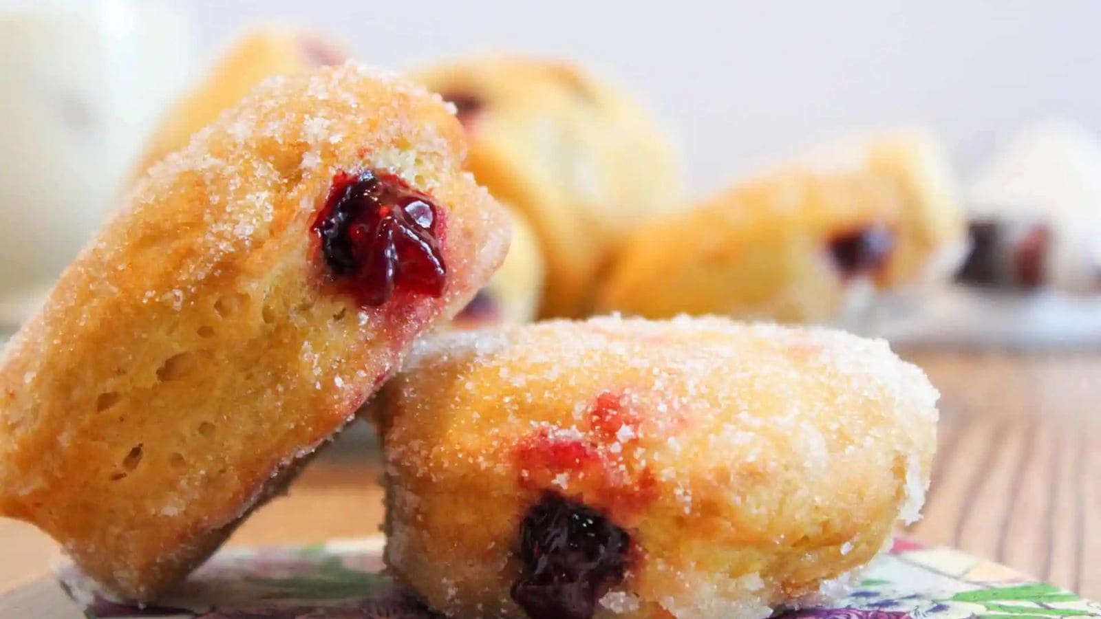 Air fryer jelly donuts filled with jam and coated in sugar.