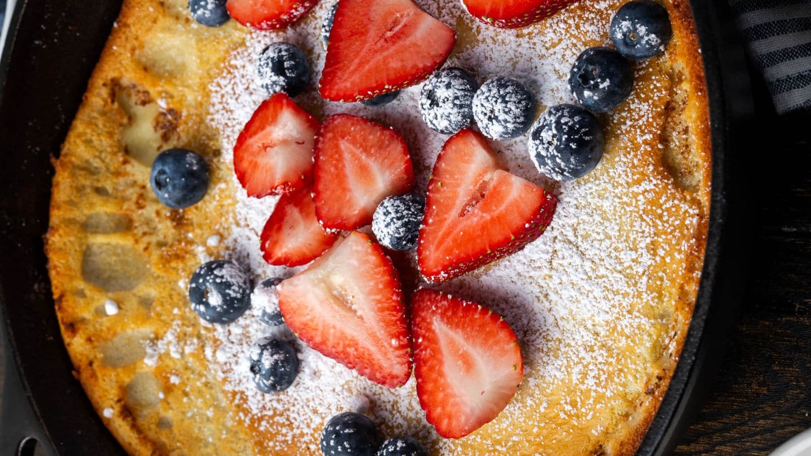 Cast iron Dutch baby pancake with crisp edges and a soft, airy center.