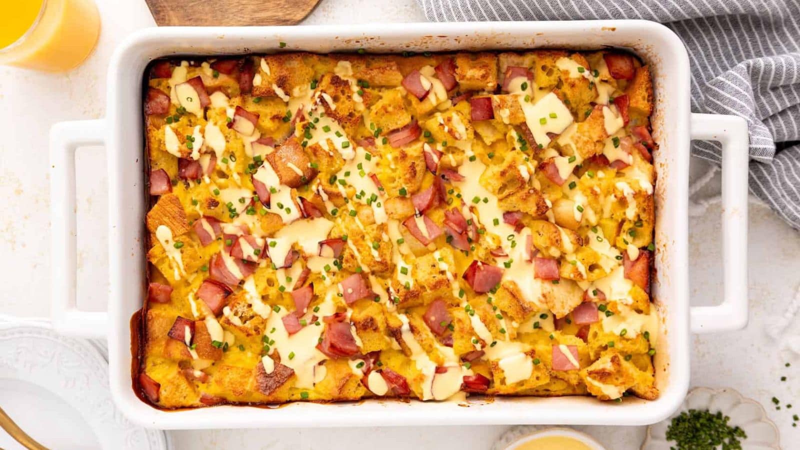 Eggs Benedict casserole with English muffins, ham, eggs, and creamy sauce.