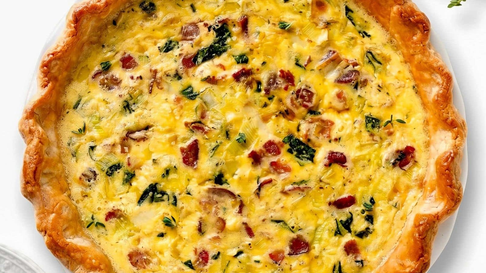 Bacon spinach and leek quiche with a savory filling in a flaky crust.