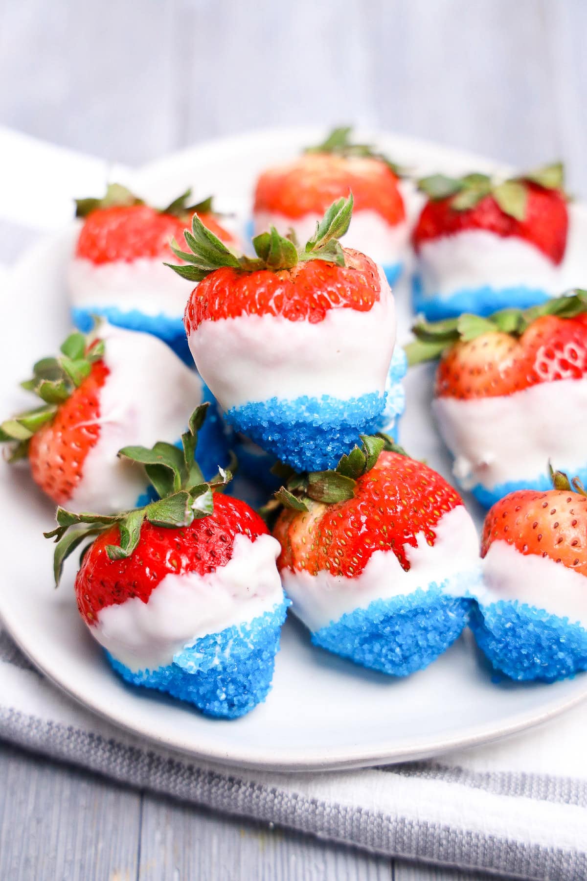 Red white and blue chocolate covered strawberries with sugar crystals on plate.