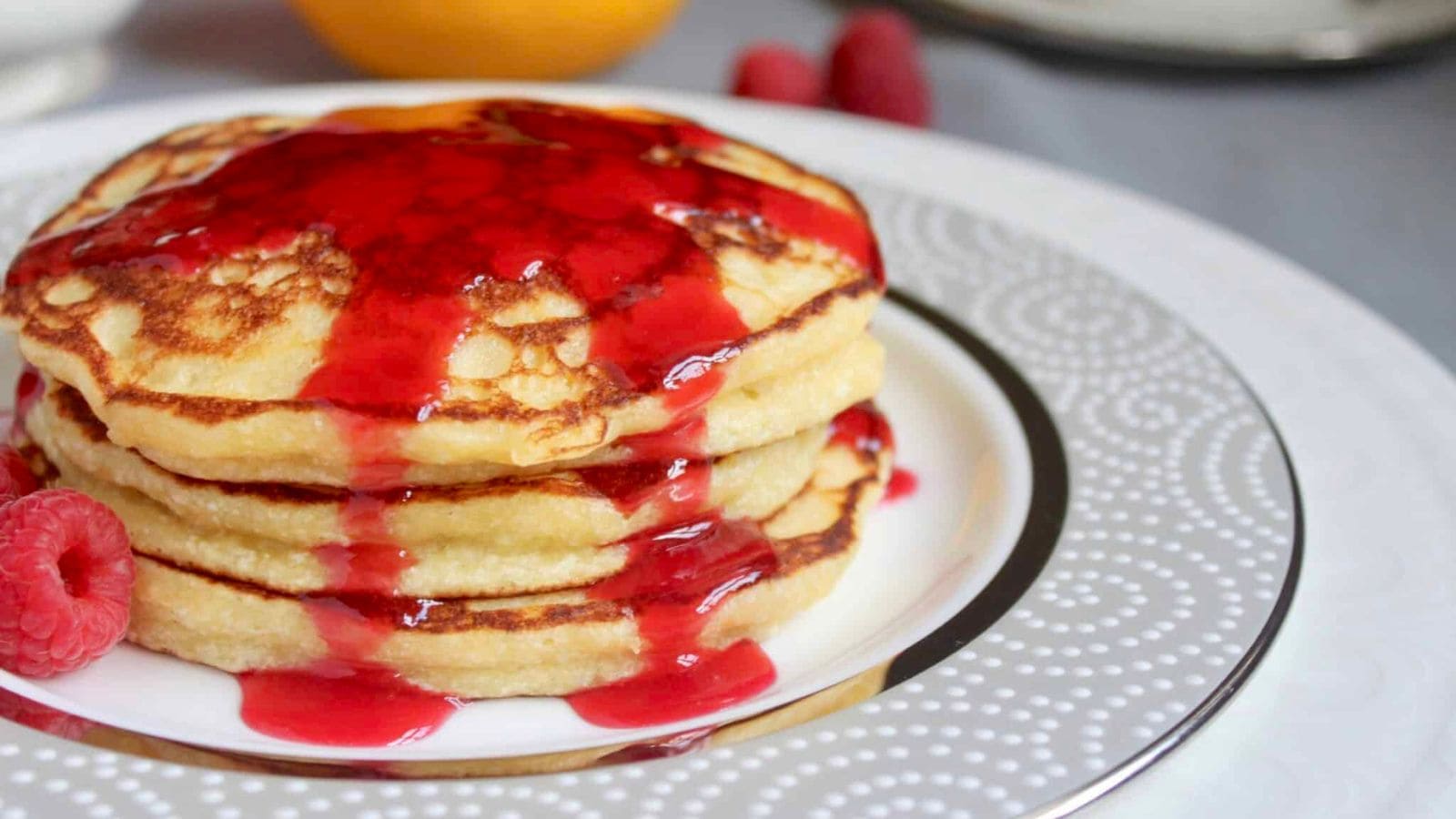 Lemon souffl&eacute; pancakes topped with raspberries and powdered sugar.