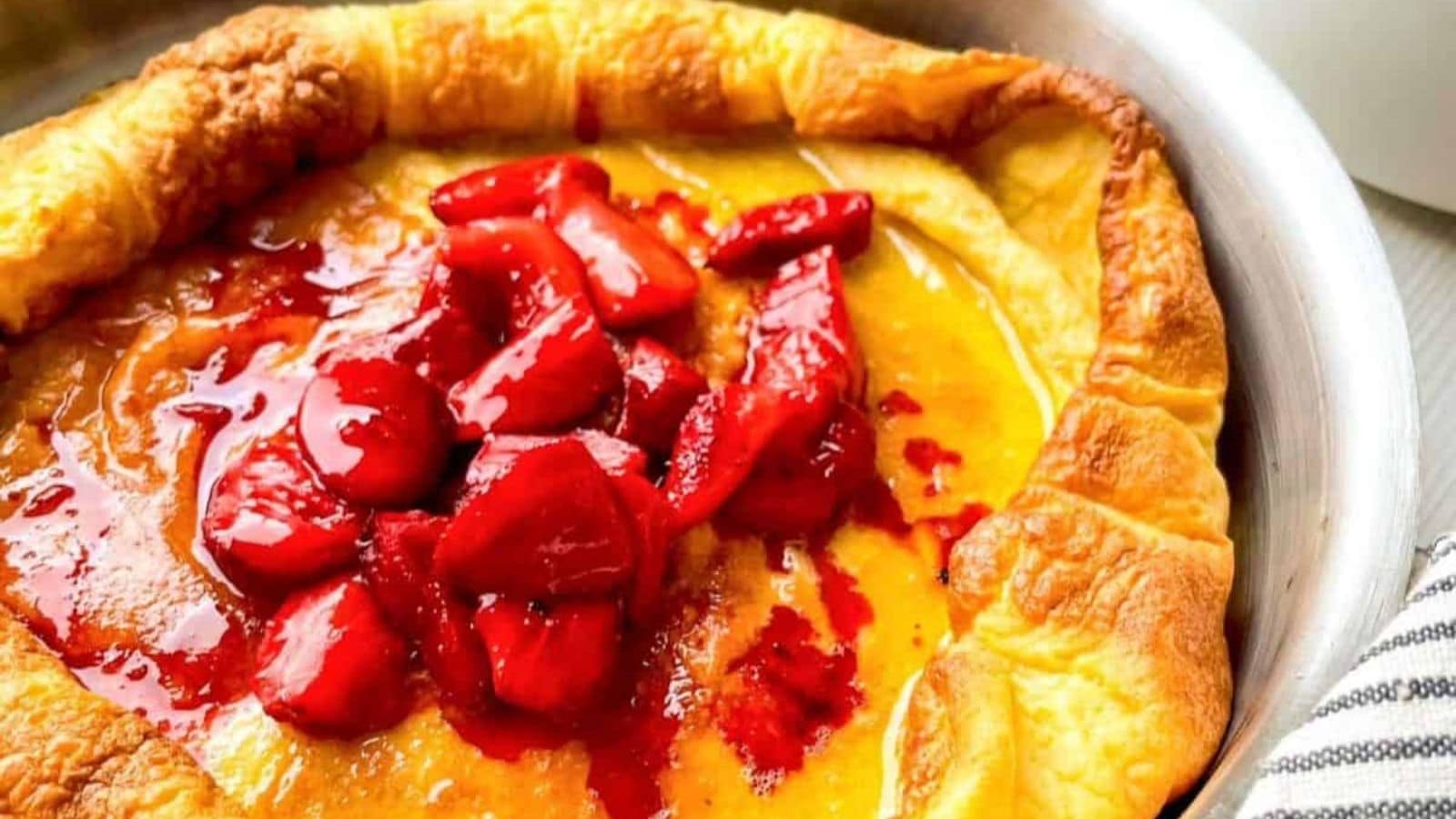 Puffy strawberry Dutch baby pancake with fresh berries and a light dusting of sugar.