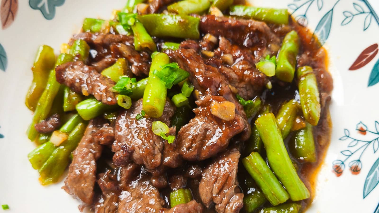 Beef and green beans stir fry with garlic and savory sauce on a plate.