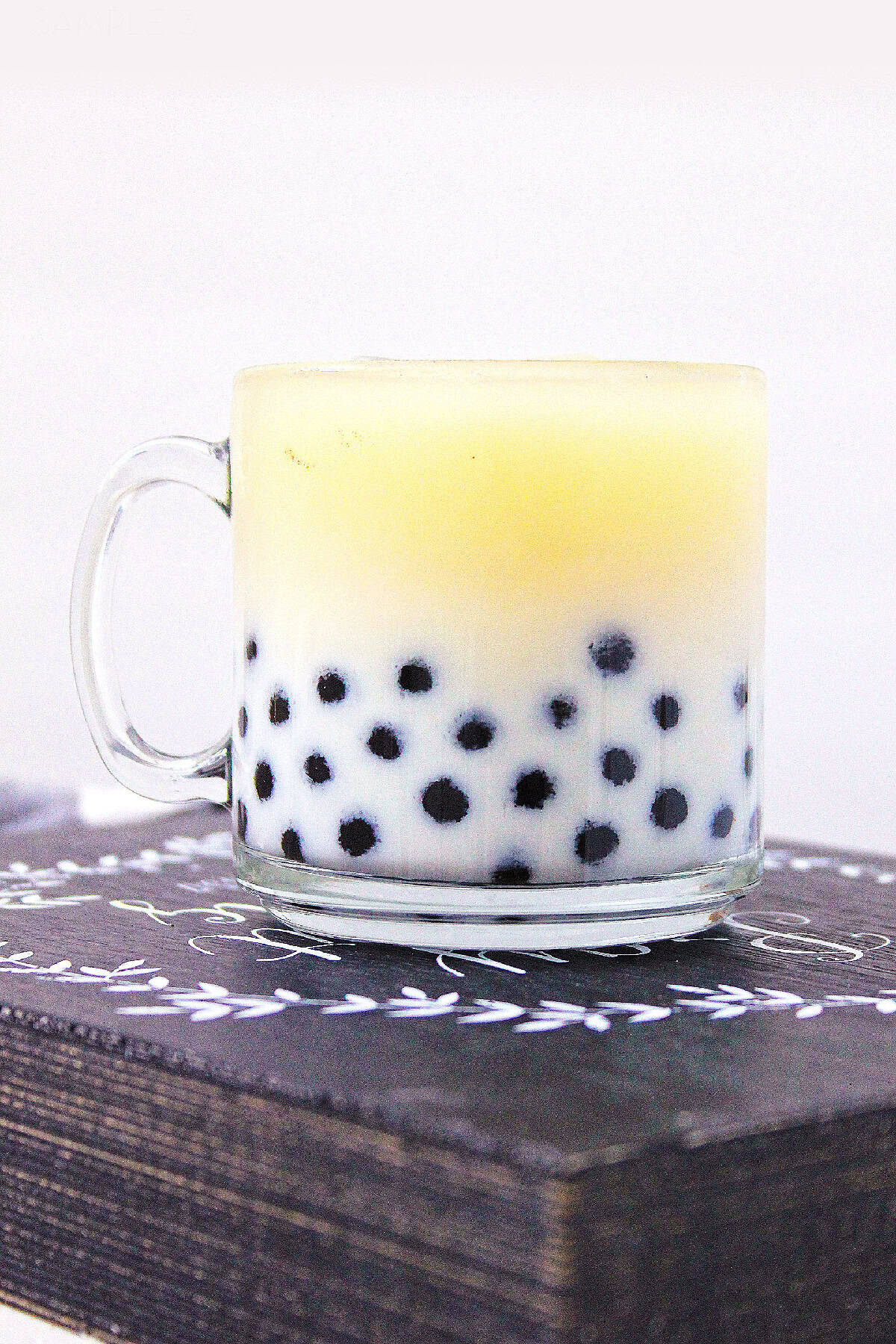 Layered milk tea with tapioca pearls in a glass mug on white background.