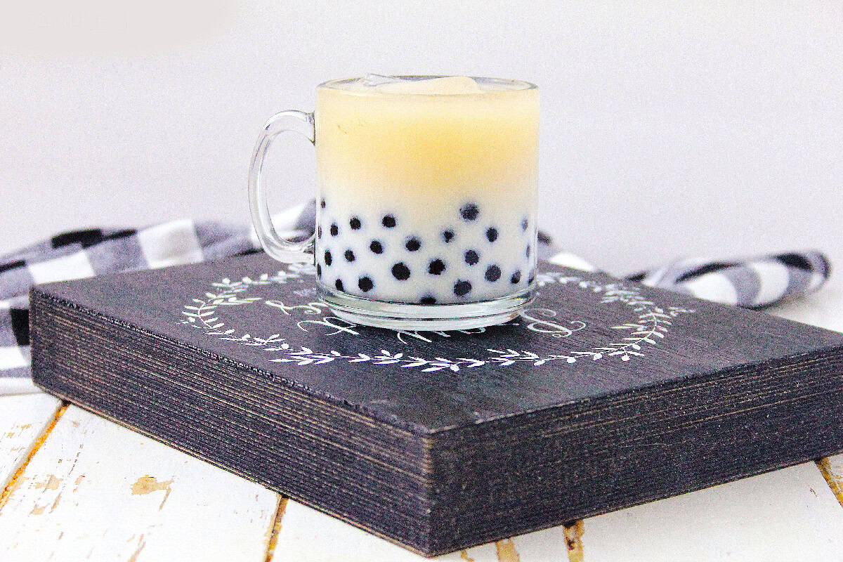 Homemade milk tea with boba pearls on a rustic serving board.