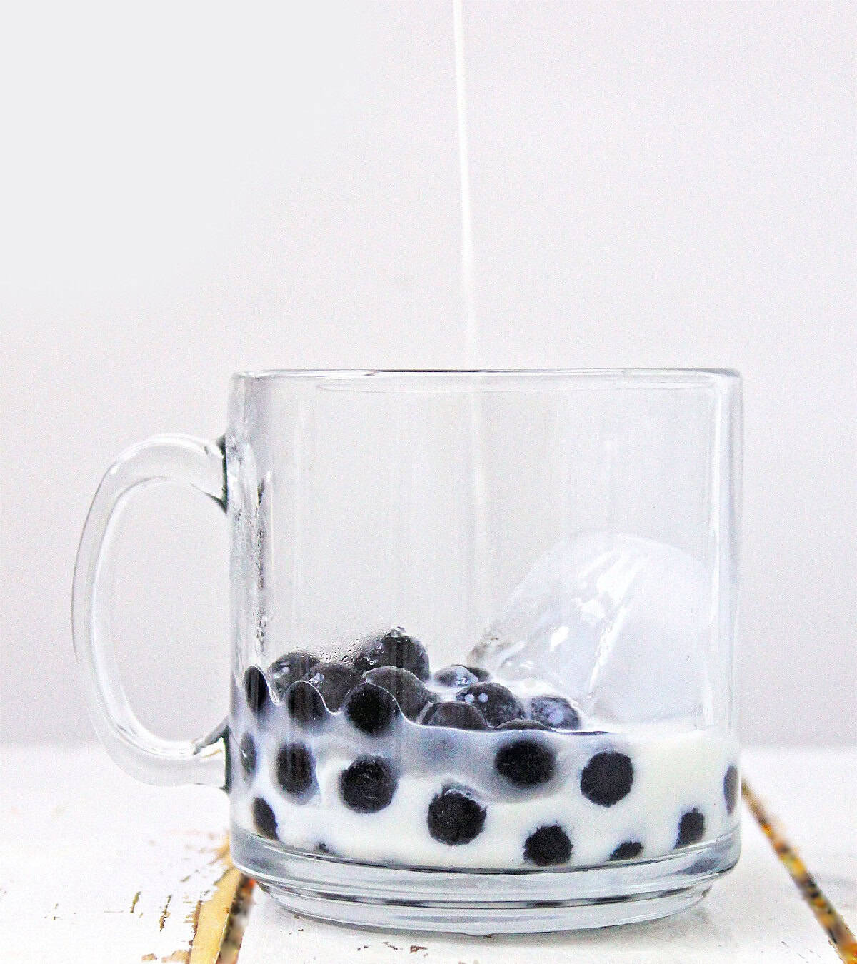 Freshly brewed tea being poured into milk and boba pearls.