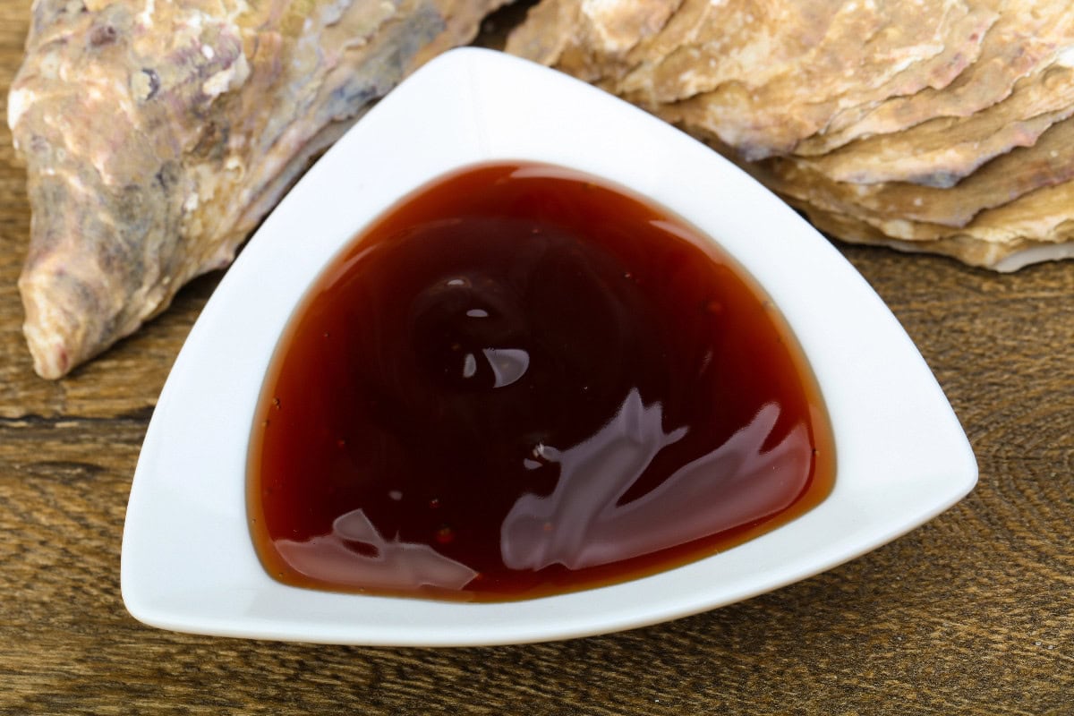 Hoisin sauce in a white dish with fresh oysters in the background.
