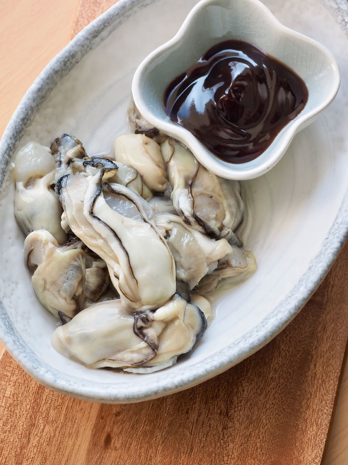 Fresh oysters served with oyster sauce in a small dipping bowl.
