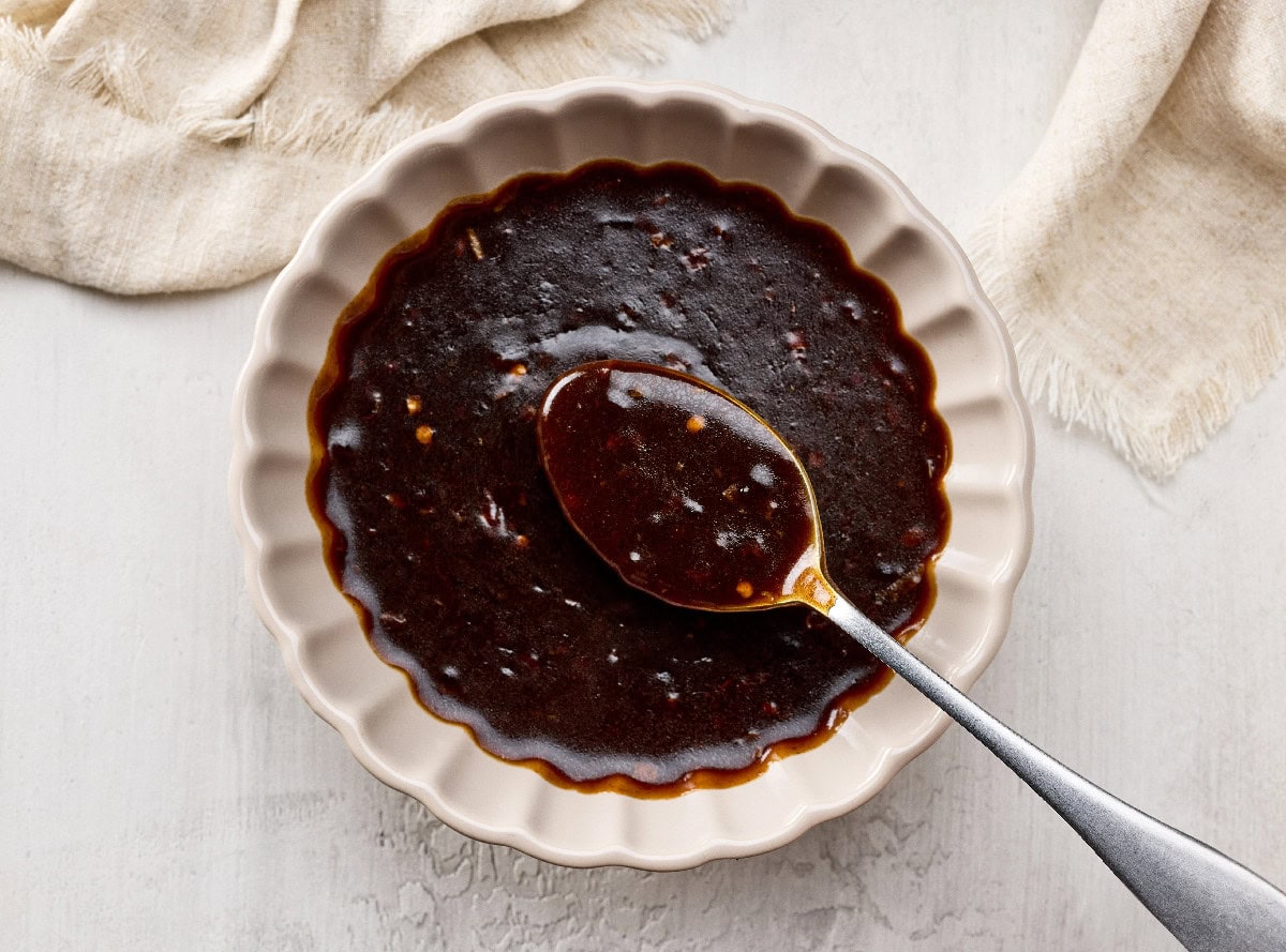 Thick hoisin sauce in a bowl with a spoon showing its texture.