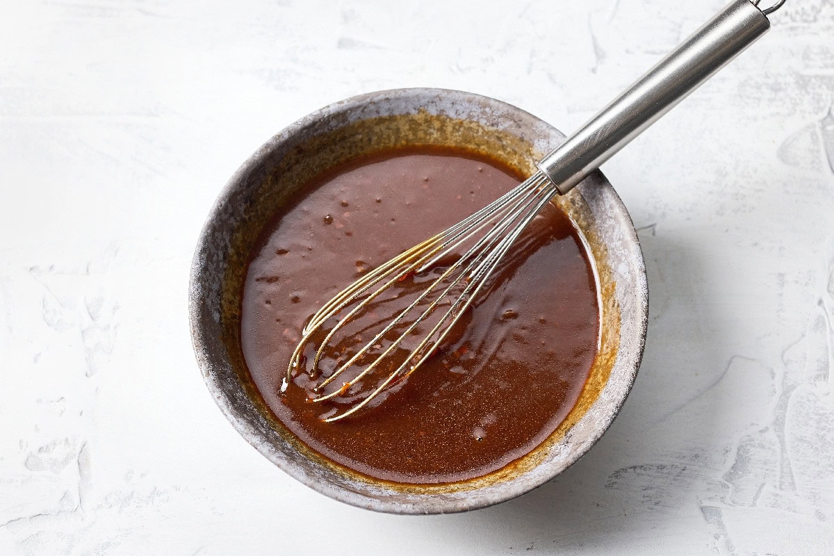 Oyster sauce being mixed in a bowl with a whisk.
