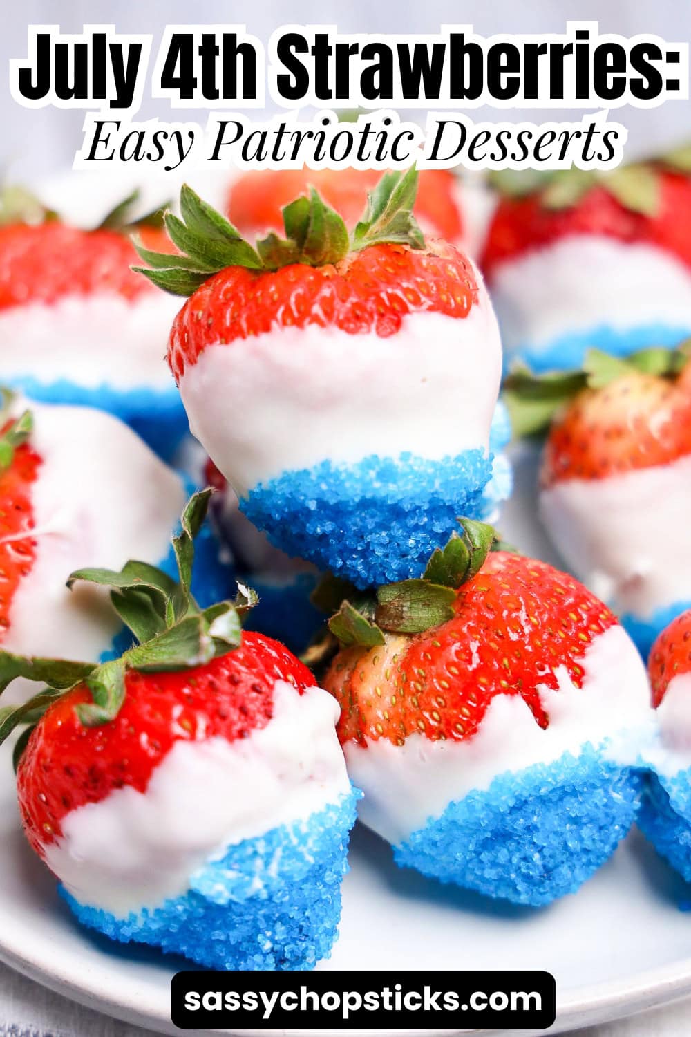 July 4th strawberries dipped in white chocolate with blue sugar crystals on white plate.