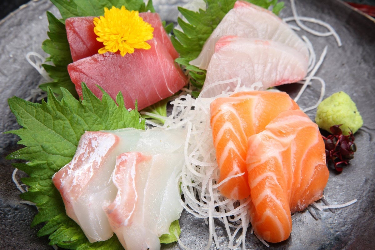 Assorted sashimi platter with salmon, tuna, and white fish served with shredded daikon and wasabi.