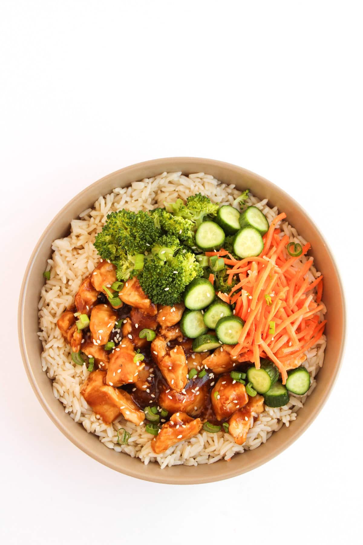 Teriyaki chicken rice bowl with green onions, and fresh vegetables.