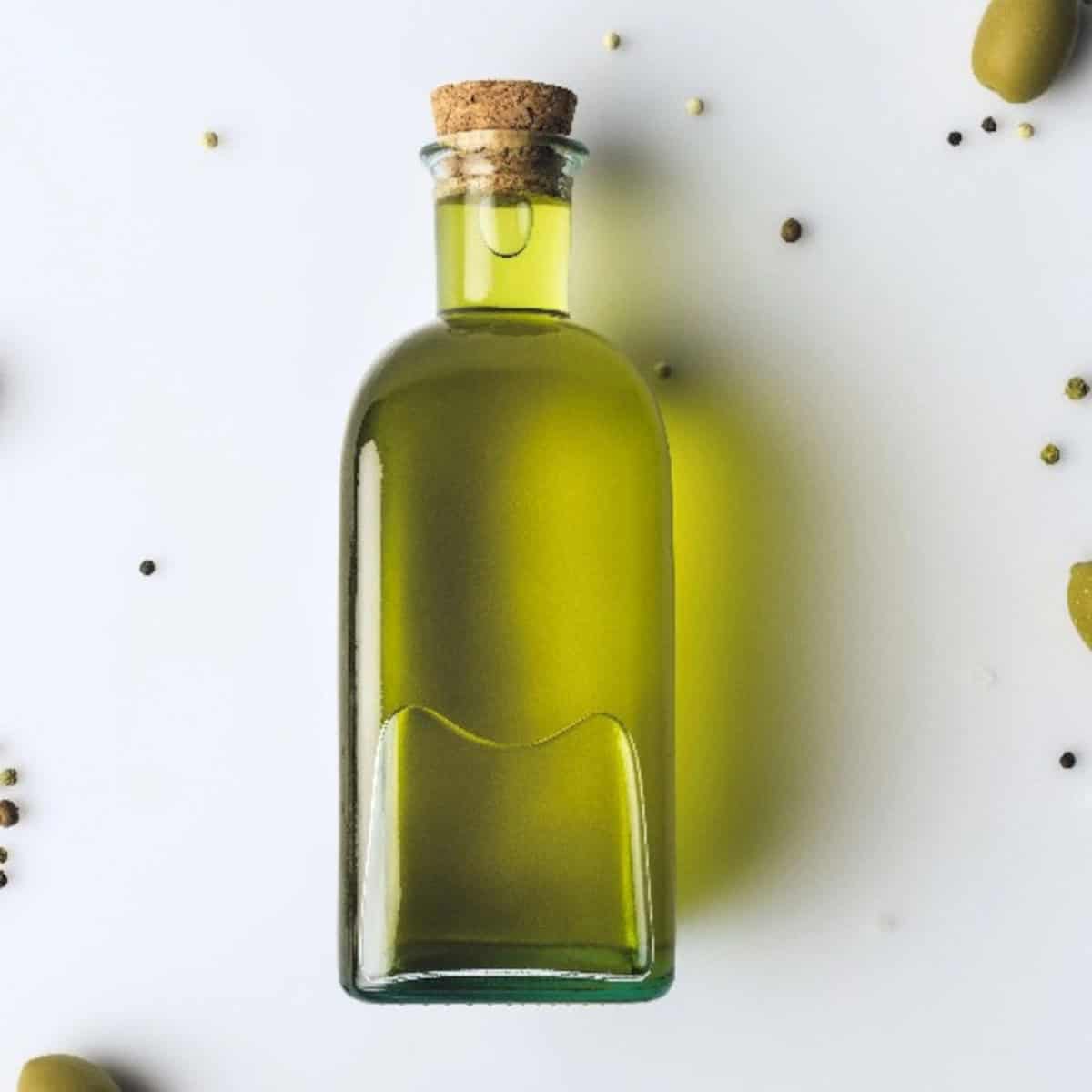 Extra virgin olive oil in a glass bottle with olives, a heart-healthy vegan fat source.