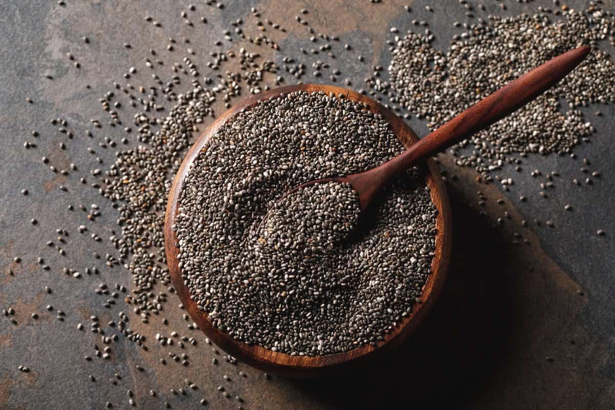 Chia seeds in a wooden bowl with a spoon, a popular vegan source of fiber and healthy fats.