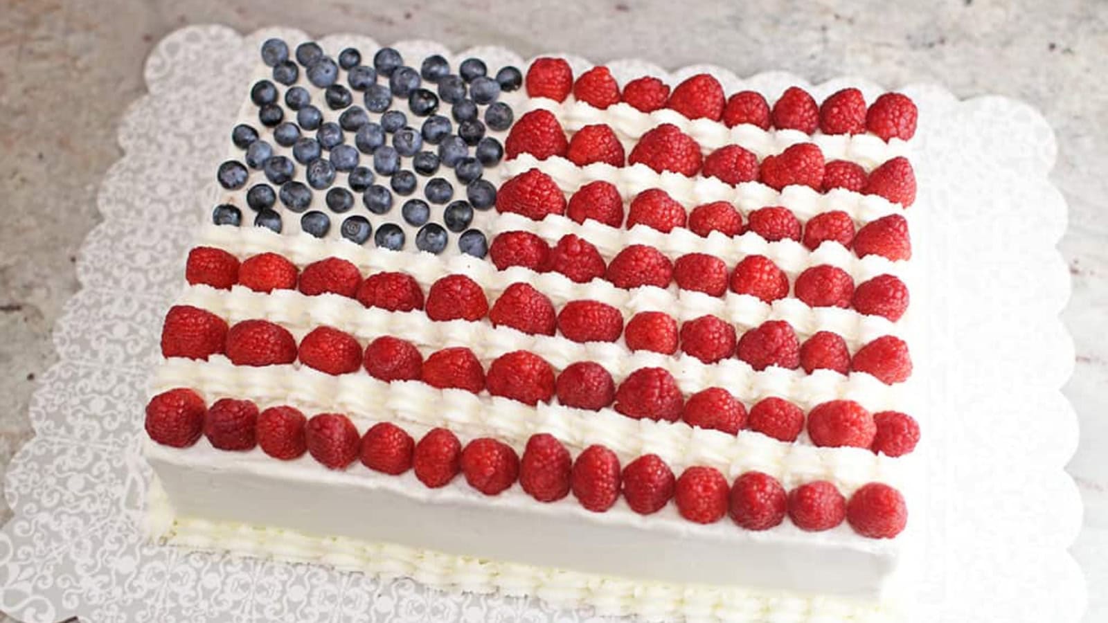Sheet cake decorated like an American flag with berries and frosting.