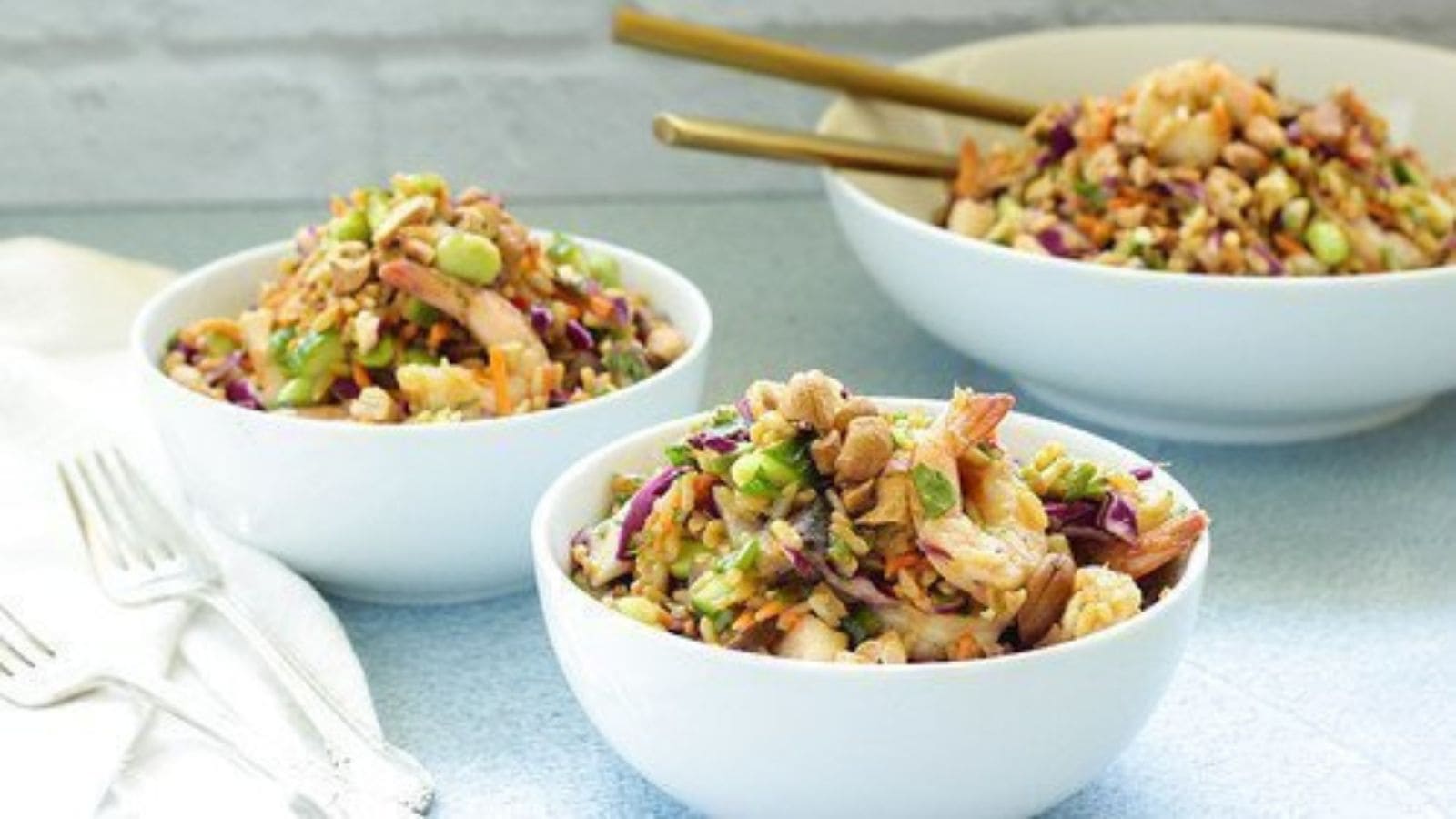 Asian rice salad mixed with shrimp and colorful vegetables in a vibrant bowl.