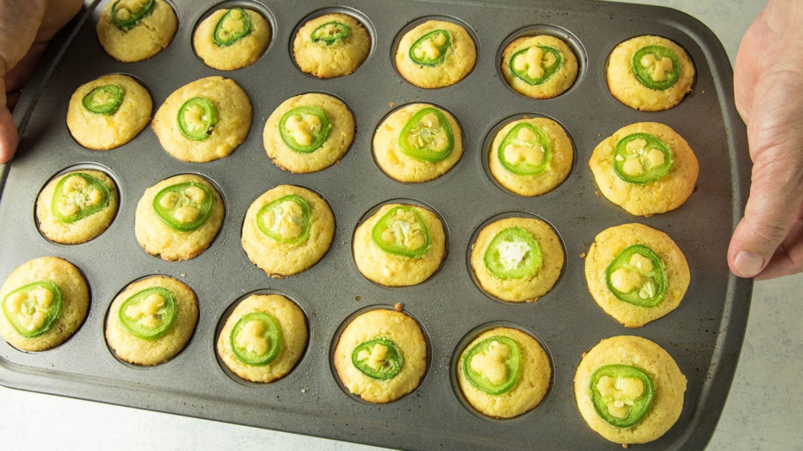 Cornbread muffins filled with jalapeños and melted cheese in a savory bite.