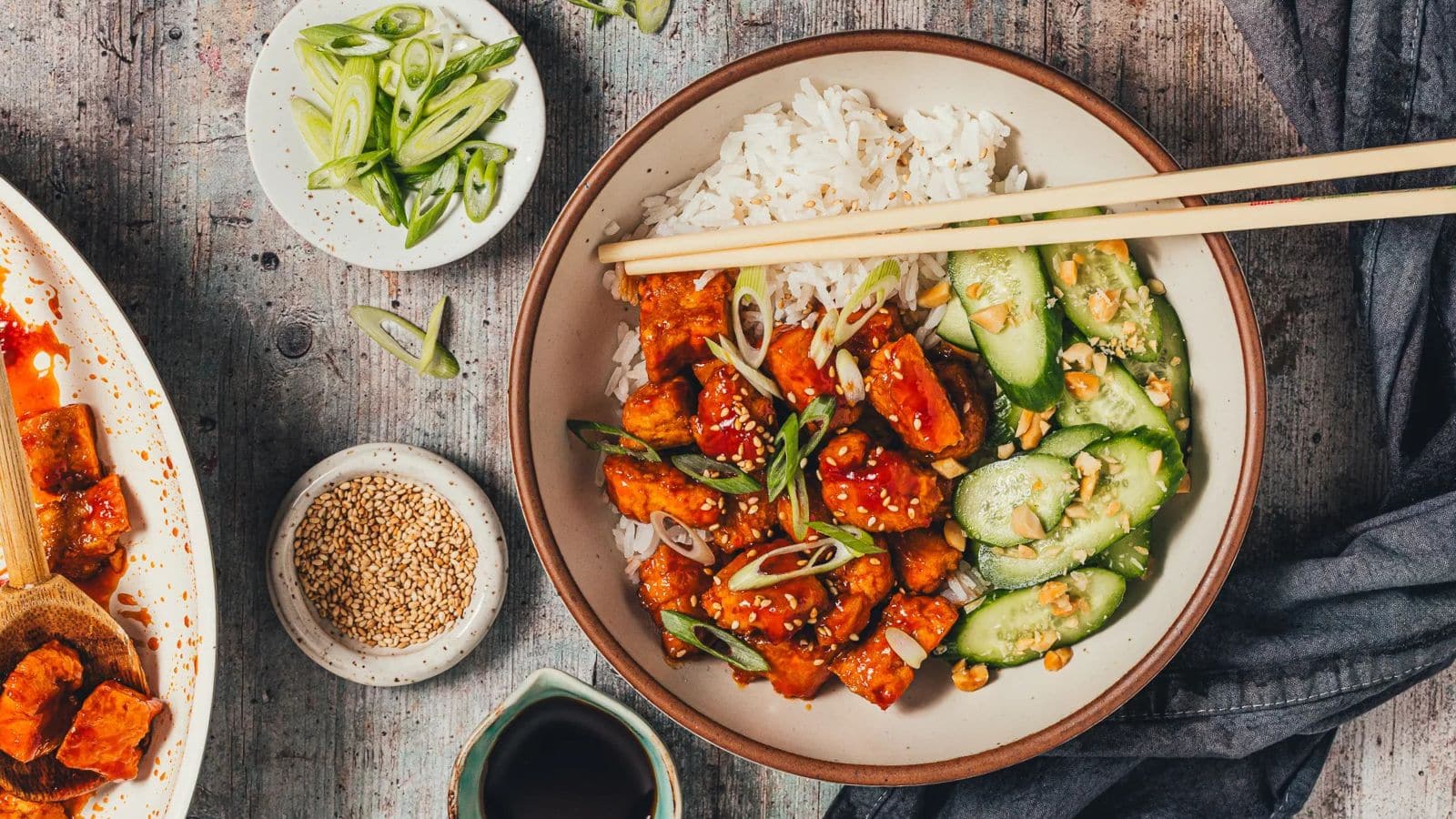 Tofu rice bowl served with spicy sauce and cucumber peanut salad.