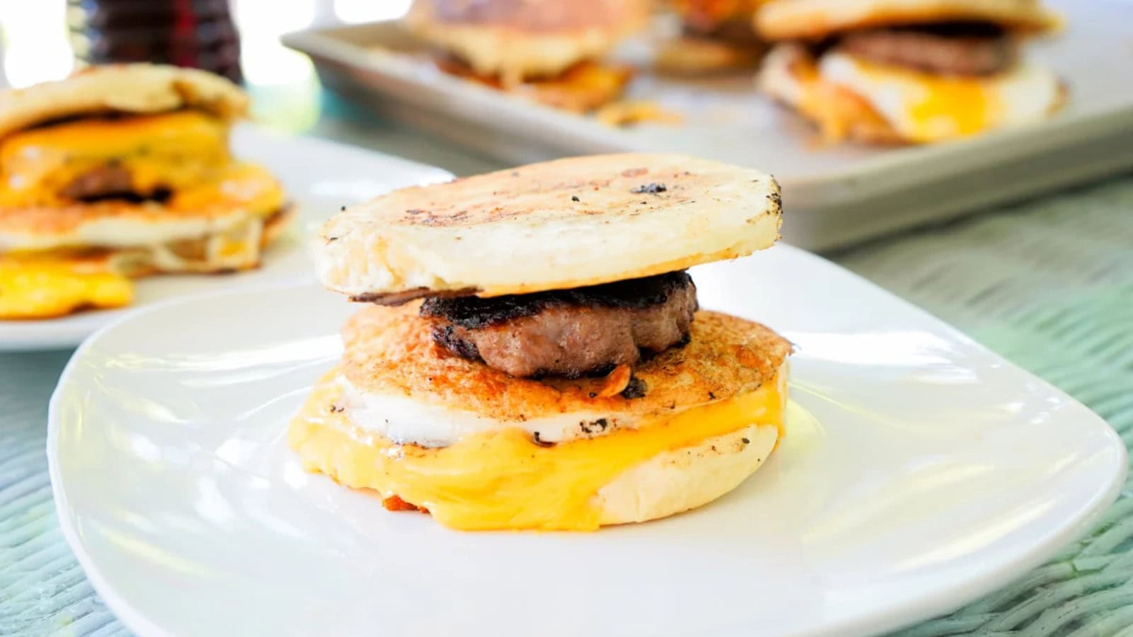 Breakfast sandwiches stacked with eggs, sausage, and pancake-style buns.