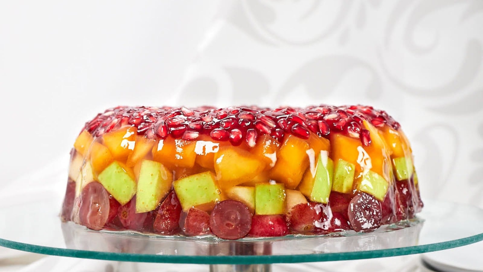 Jello cake layered with fruit pieces and colorful gelatin.