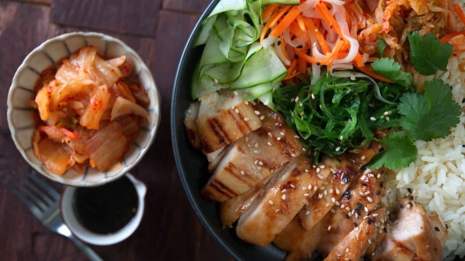Rice bowl topped with kimchi and savory vegetables.