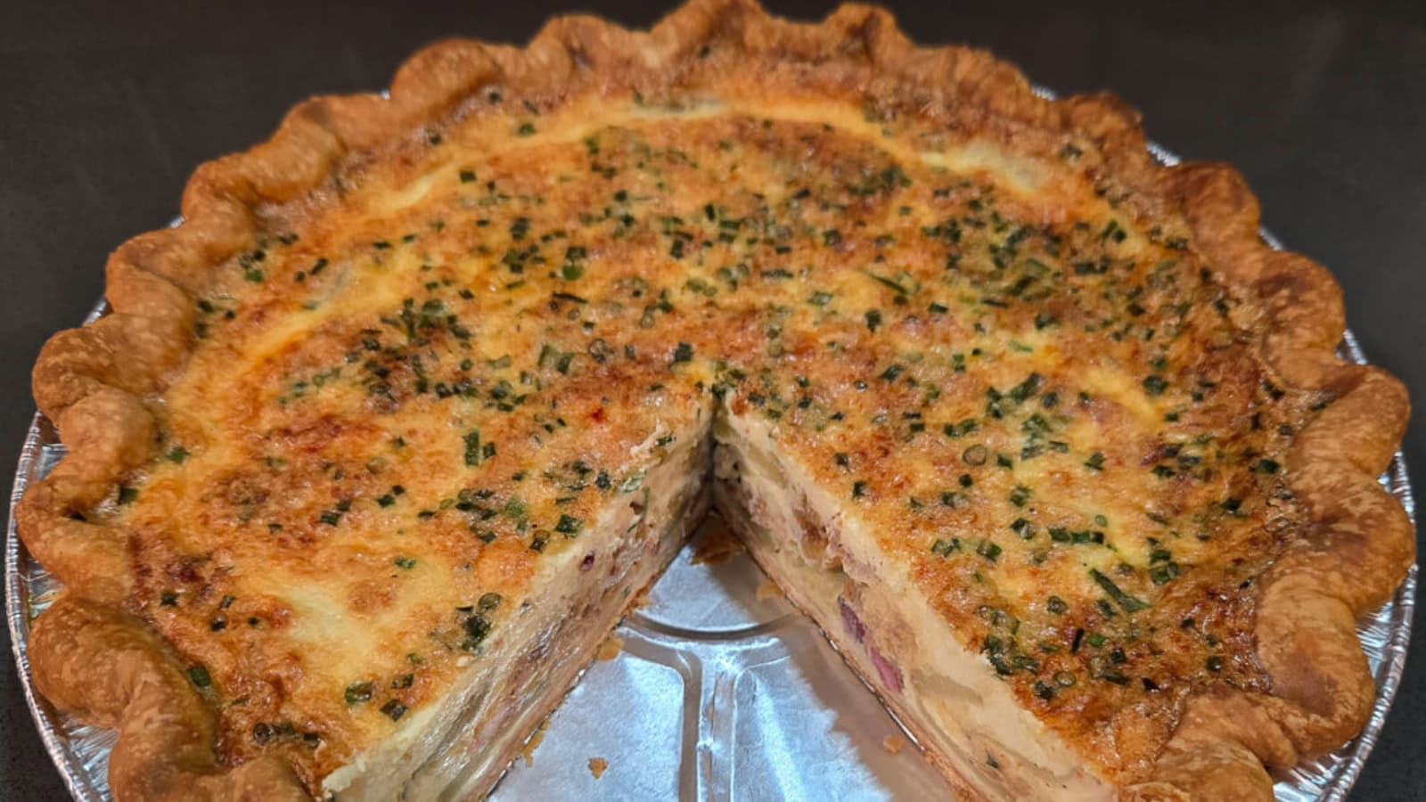 Quiche filled with potatoes, cheese, and savory toppings in a flaky crust.