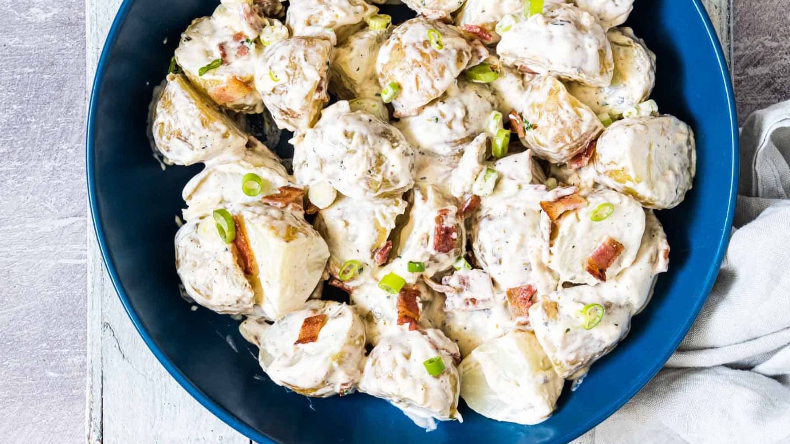 Potato salad mixed with ranch dressing and savory toppings.
